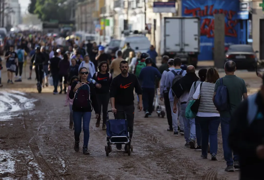 Vecinos del barrio de La Torre, en Valencia, se desplazan a otras zonas menos afectadas por la dana para poder comprar alimentos.